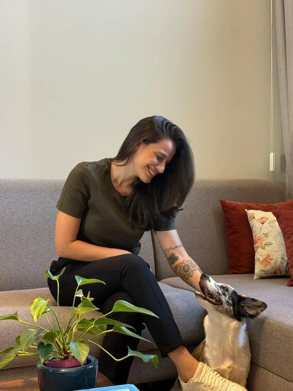 Dra. Mariana Neves sentada no sofá fazendo carinho em um cachorro